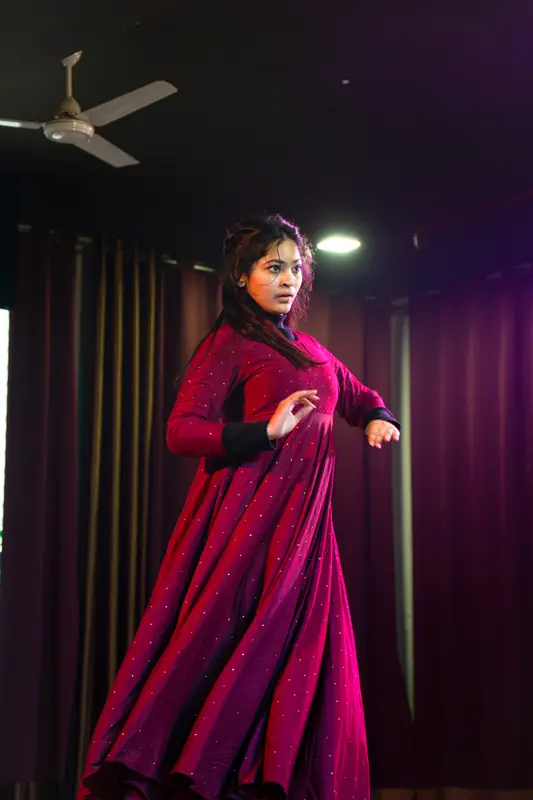 A Kathak dancer in a red anarkali on stage