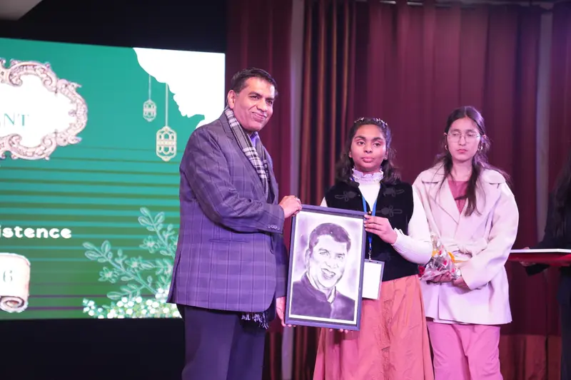 Two students present a hand-drawn portrait to a guest on stage