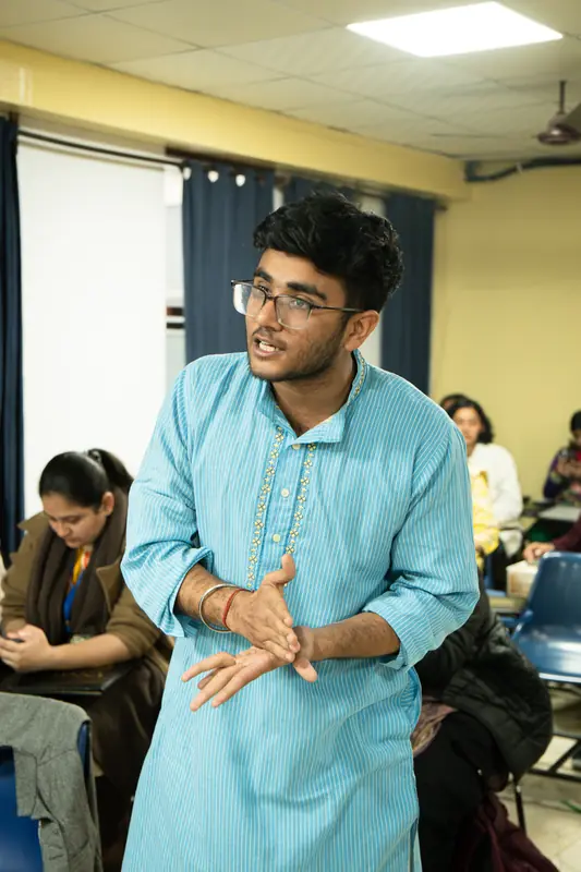 A delegate in a blue kurta stands to speak in committee