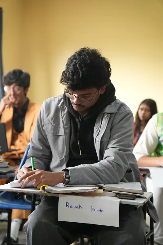 A delegate writing notes at a desk during a session